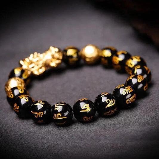 Wealth Attractor Black Obsidian Bracelet with glossy black beads, gold symbols, and a sculpted gold-tone charm